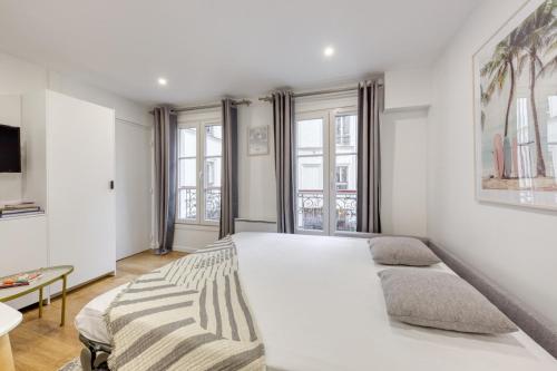 - une chambre blanche avec un grand lit blanc et des fenêtres dans l'établissement Le Balcon de l'Opéra I Studio Cozy, à Paris