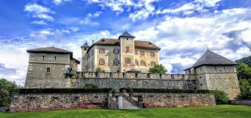 een groot kasteel met twee torens bovenop een stenen muur bij B&B Vivi l'Attimo in Campodenno