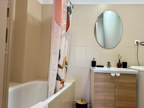 uma casa de banho com uma banheira, um lavatório e um espelho. em Douce Agathe - Duo-Groupe, Chaleureux, Tram 200m, Centre 10min em Estrasburgo