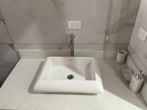 a white sink with a faucet in a bathroom at Alojamiento Kim House Orotina in Orotina