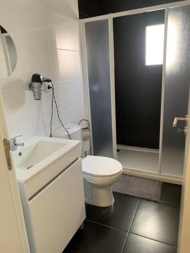 a white bathroom with a toilet and a sink at Maison de vacances in Pombal