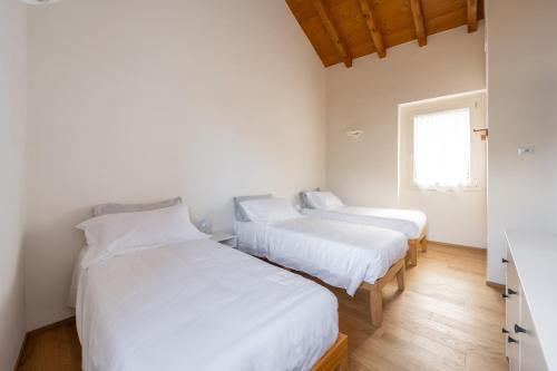 two beds in a room with white walls and wooden floors at New stone house lake view - 2 in Lezzeno