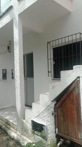 een wit gebouw met een houten deur en trap bij Vanu in Morro de São Paulo