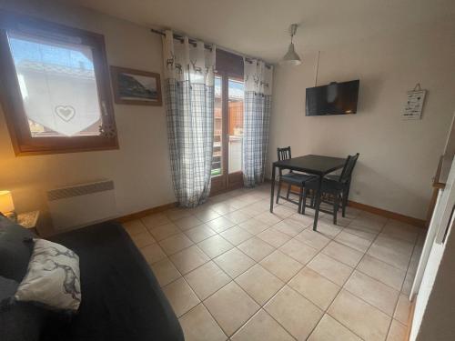 un salon avec une table, des chaises et une télévision dans l'établissement Petit Praz, à Praz-sur-Arly