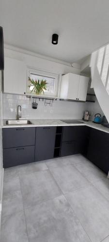 a kitchen with white cabinets and a sink and a window at WAVEhouse Pobierowo in Pobierowo