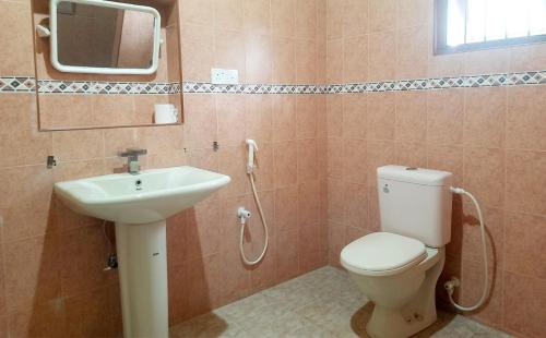 ein Badezimmer mit einem WC, einem Waschbecken und einem Spiegel in der Unterkunft Leyon-Tourist Inn in Negombo