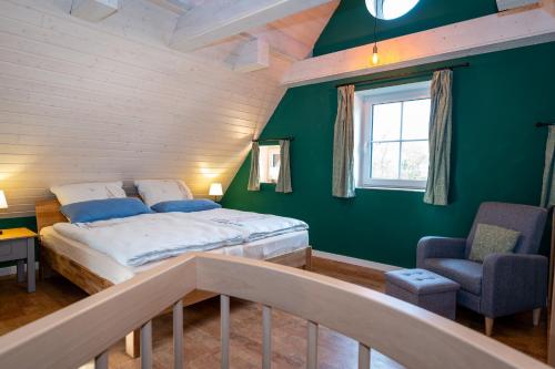 a bedroom with green walls and a bed and a chair at Ferienhaus Lee in Pellworm