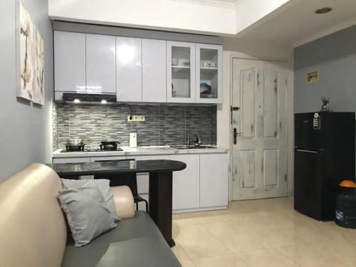 una cucina con armadietti bianchi e frigorifero nero di Apartement Mediterania Palace Jakarta pusat a Giacarta