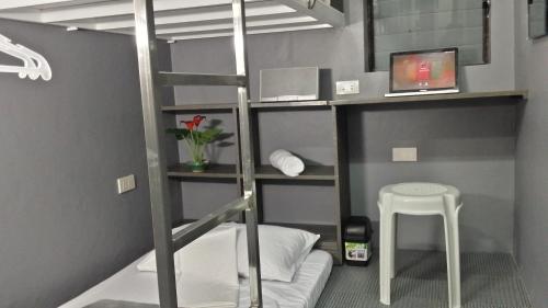a bunk bed with a ladder and a stool in a room at ERVORUTO HOSTEL 23 Makati in Manila