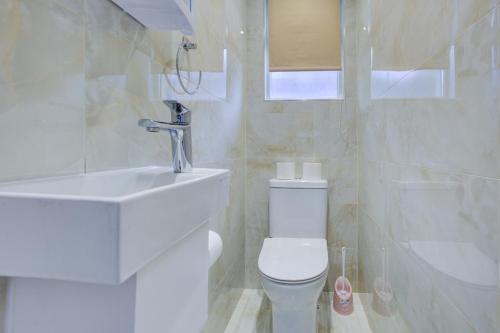 Baño blanco con aseo y lavamanos en Streatham Hotel, en Londres