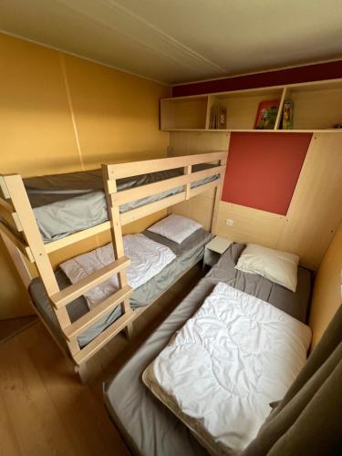 Cette chambre comprend deux lits superposés et un lit. dans l'établissement GRAIN DE SABLE - Mobil Home climatisé 5 pers - 100m de la mer - Le Portel, à Le Portel