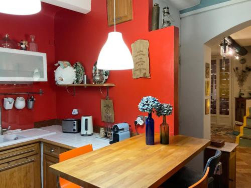 a kitchen with a wooden table and a red wall at Amiradou in Éguilles