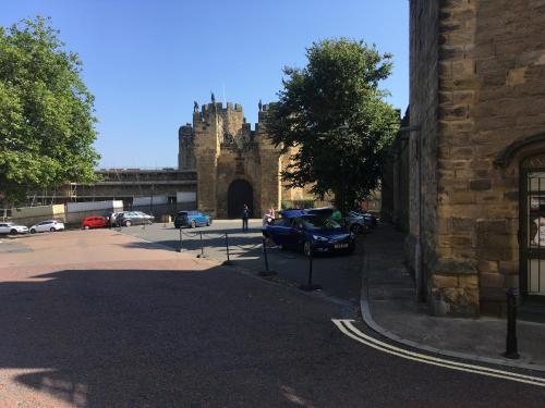 a car parked in front of a building with a castle at Barbican View - luxury apartment opposite Alnwick Castle in Alnwick