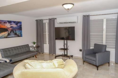 a living room with a couch and a tv and a chair at EcoMar Rentals in Cabo Rojo