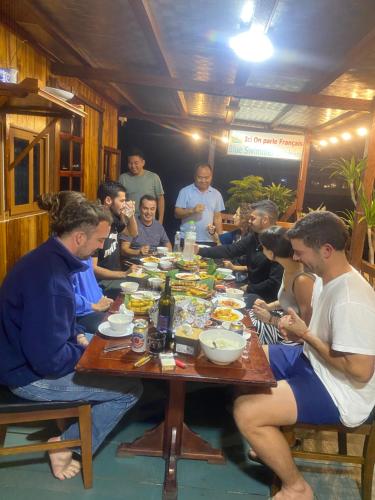 a group of people sitting around a table eating food at Eco Floating Farm Stay Cai Beo in Cat Ba