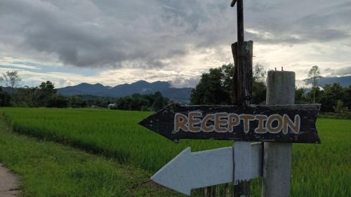 Ein Schild, auf dem steht: Empfang neben einem Reisfeld in der Unterkunft Chill In Pai - ชิลล์ อิน ปาย in Pai