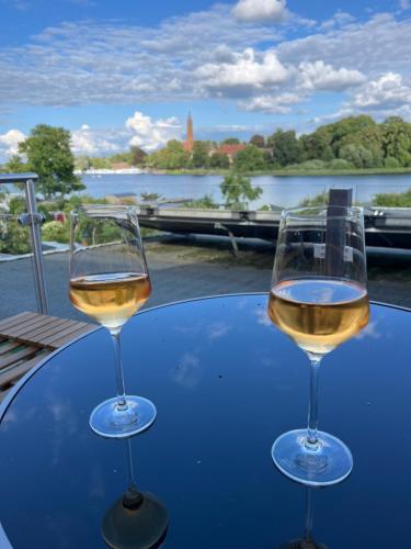 dos vasos de vino blanco sentados en una mesa en Ferienhaus Seekutter mit eigenem Seezugang en Malchow
