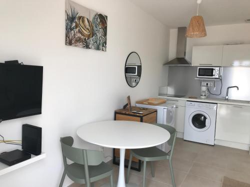 - une cuisine avec une table blanche, des chaises, une table et un évier dans l'établissement Studio en bord de mer sur Costa Serena N54, à Linguizzetta