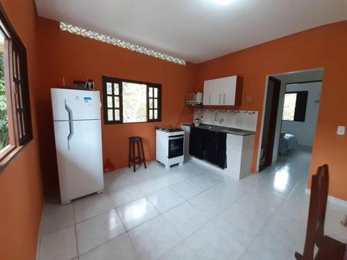 eine Küche mit orangefarbenen Wänden und einem weißen Kühlschrank in der Unterkunft Casa sobreposta alta em Boiçucanga - São Sebastião in São Sebastião