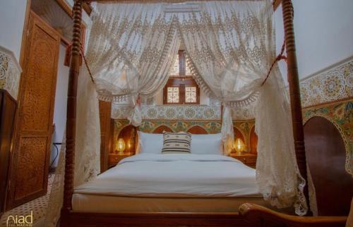 a bedroom with a canopy bed with white curtains at Riad Fes Madaw in Fès