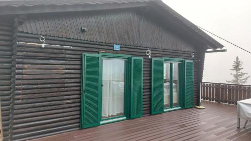 a small building with green shutters on a deck at Nussknackerhaus in Sankt Kanzian