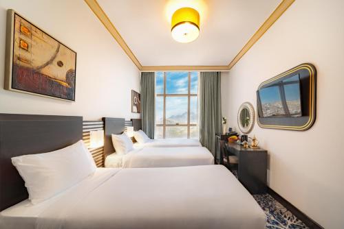 メッカにあるAl Kiswah Towers Hotelのベッド3台とテレビが備わるホテルルームです。