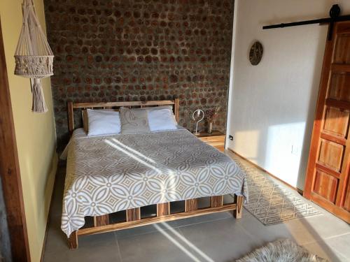a bedroom with a bed and a brick wall at Nativo Lodge Cabaña in Playas