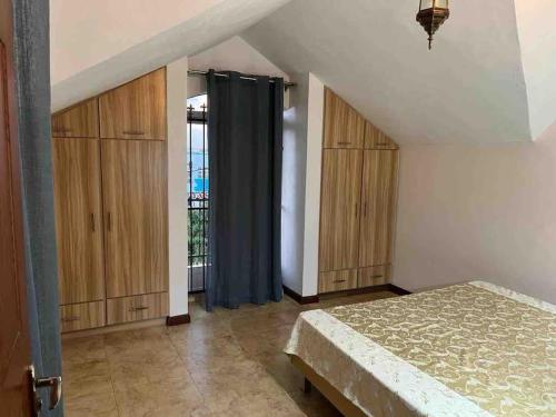 1 dormitorio en el ático con 1 cama y armarios de madera en * La Petite Villa * Golf de Mont Choisi *, en Mont Choisy