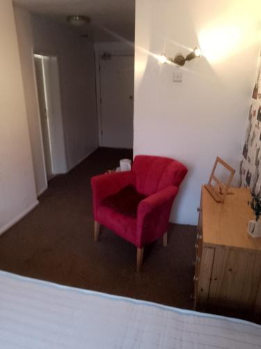 a living room with a red chair and a dresser at The monk in Towcester