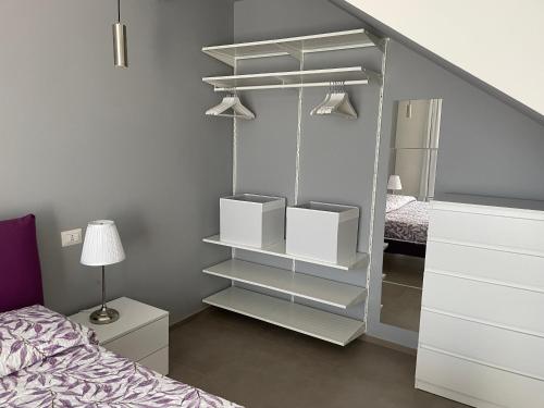 a bedroom with a closet with white shelves and a bed at Polinesia 12 in Lido delle Nazioni
