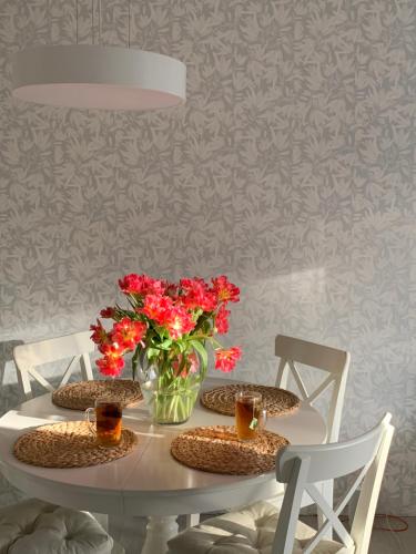 uma mesa branca com um vaso de flores e cadeiras em Palūšės Apartment em Paluse