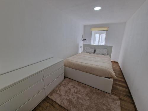 a white bedroom with a bed and a window at Azores Square House historic city center in Ponta Delgada