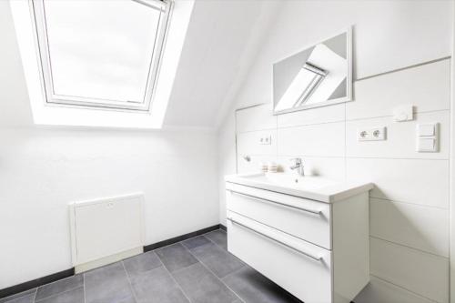 een witte badkamer met een wastafel en een spiegel bij Ferienhaus Siedlerstraße in Leer