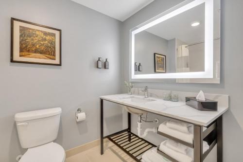 a bathroom with a sink and a toilet and a mirror at The Kingston in Savannah