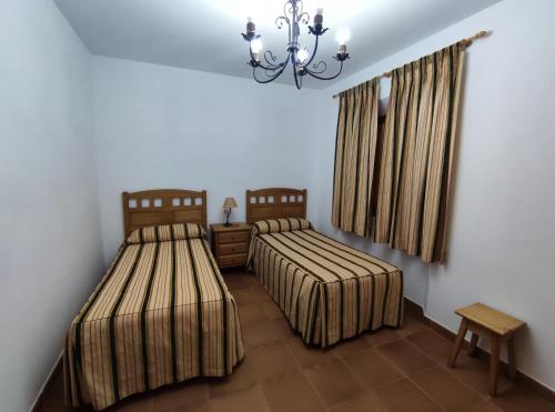 a bedroom with two beds and a chandelier at Casa Rural María Victoria in Navas de Estena