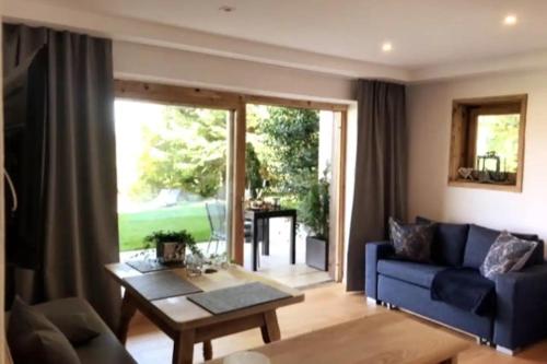 ein Wohnzimmer mit einem blauen Sofa und einem Tisch in der Unterkunft Haus Hochland - Moderne Alpenwohnung Garten&Natur in Bad Kohlgrub