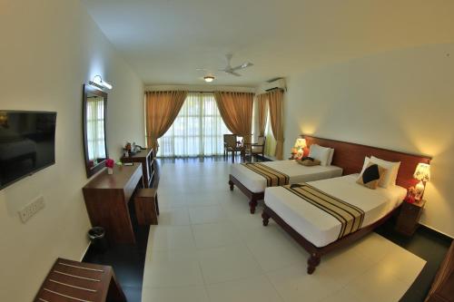 um quarto de hotel com duas camas e uma televisão em Passi Villa em Pasikuda