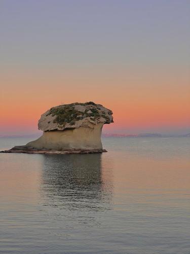 a small island in the water at sunset at Arime Apartment in Ischia