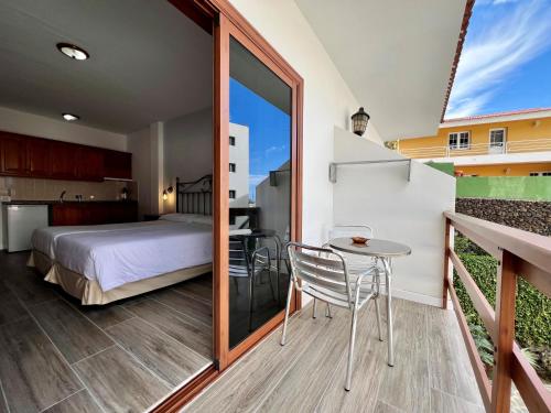 1 dormitorio con cama, mesa pequeña y balcón en Apartamentos Frontera, en La Frontera