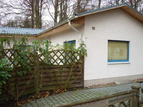 una casa blanca con una valla de madera delante de ella en Bungalow Quooß GM 69657, en Graal