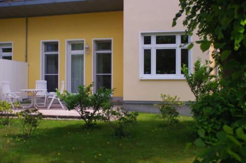 a yellow house with a table and chairs in a yard at Ferienwohnung Bülow GM 69131 in Müritz