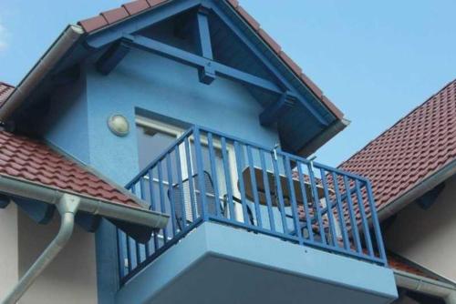 un balcón azul en una casa con techo rojo en Ferienwohnung Seeanemone I - GM 69353, en Graal