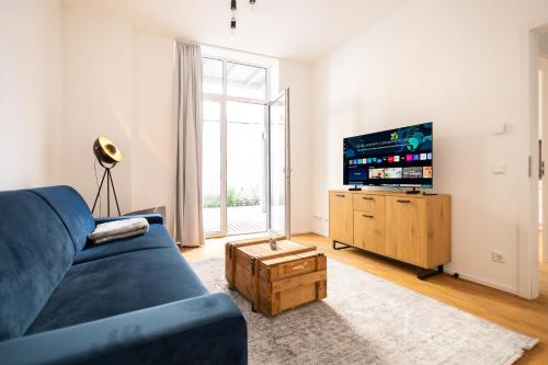 a living room with a blue couch and a tv at Ko-Living - Beatles und Banksy Suites & Studios am Eselsbrunnen - Altstadt - Küche in Halle an der Saale