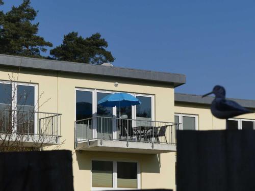 a building with a balcony with a blue umbrella at Ostseebuhne GM Schwerdtner in Müritz