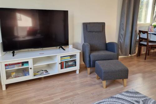 a living room with a flat screen tv and a chair at Villa Silve, yhden makuuhuoneen omakotitalo. in Lohja