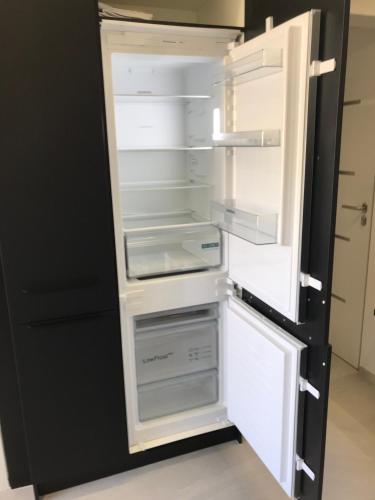un réfrigérateur vide avec sa porte ouverte dans une cuisine dans l'établissement Neue Moderne Ferienwohnung, au Cap d'Agde