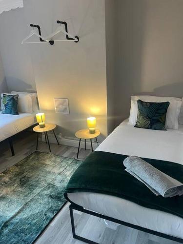 a bedroom with two beds and two tables with candles at Affordable Newly Refurbished 3 Bedroom House, Sleeps 7, NG8 Postcode in Nottingham