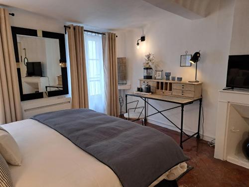 a bedroom with a bed and a desk with a television at Hôtel Le Patio de Sophie in Sisteron