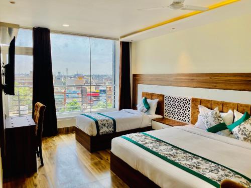 Habitación de hotel con 2 camas y ventana grande. en Hotel White house near Golden Temple, en Amritsar