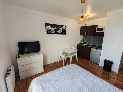 a bedroom with a bed and a small table with a television at Studio Disneyland Paris 10min/Val d'Europe 5min/Wifi/TV in Montévrain